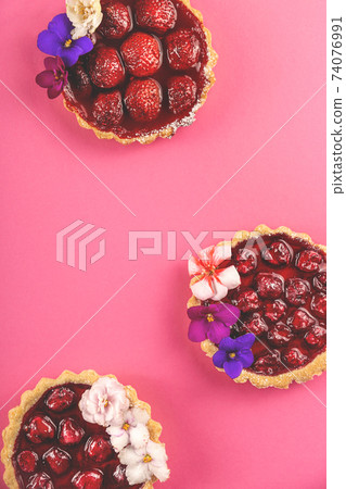 Spring homemade mini pies with berries decorated with flowers Spring homemade mini pies with berries decorated with flowers 74076991