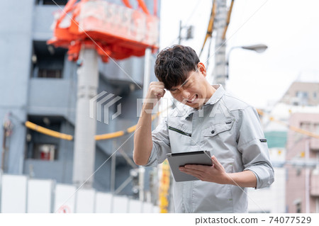 一名年輕的工人，在建築地盤工作的麻煩的臉 74077529