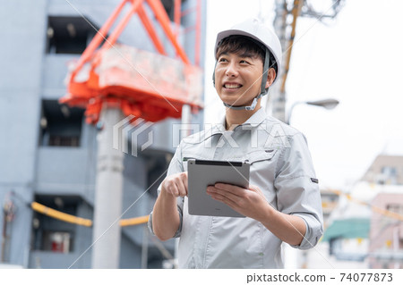 在建築地盤工作的頭盔的年輕工人 74077873