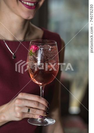woman holds relaxing alcoholic pink coctail with a rose on top woman holds relaxing alcoholic pink coctail with a rose on top 74078280