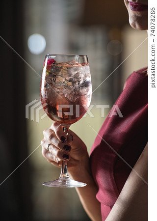 woman holds relaxing alcoholic pink coctail with a rose on top woman holds relaxing alcoholic pink coctail with a rose on top 74078286