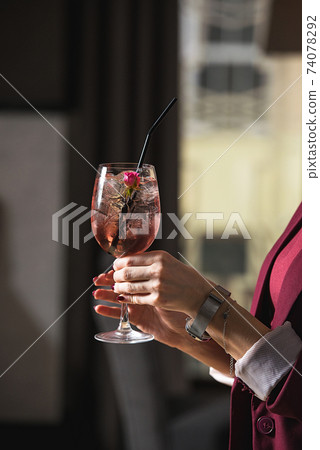 woman holds relaxing alcoholic pink coctail with a rose on top woman holds relaxing alcoholic pink coctail with a rose on top 74078292