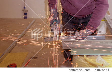 Cutting metal profile with a grinder during repair work. Lots of friction sparks Cutting metal profile with a grinder during repair work. Lots of friction sparks 74078541