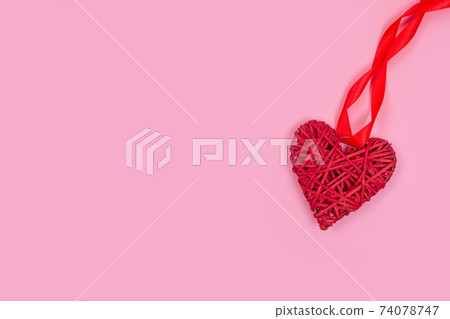 Red heart with red ribbon, symbol of love, on pink background with copy space for your text - St. Valentine's Day celebration concept. Love backdrop for greeting card, selective focus 74078747