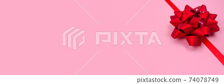 Banner with decorative red ribbon bow on pink background with copy space for text. Giving presents concept. Greeting card or holidays sale background. Selective focus Banner with decorative red ribbon bow on pink background with copy space for text. Giving presents concept. Greeting card or holidays sale background. Selective focus 74078749