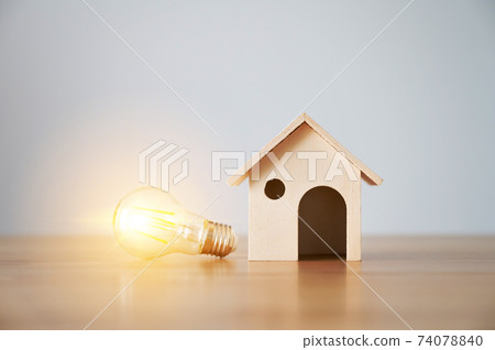 Light bulb and wooden house on the table 74078840