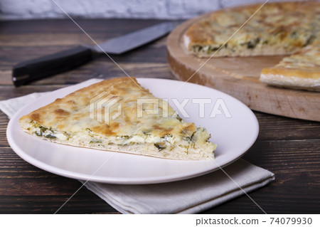 Ossetian pie with cheese and herbs (dill, parsley, scallion). Traditional Ossetian baking. Ossetian pie with cheese and herbs (dill, parsley, scallion). Traditional Ossetian baking. 74079930
