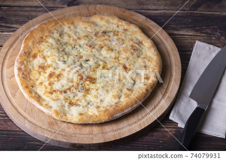 Ossetian pie with cheese and herbs (dill, parsley, scallion). Traditional Ossetian baking. 74079931
