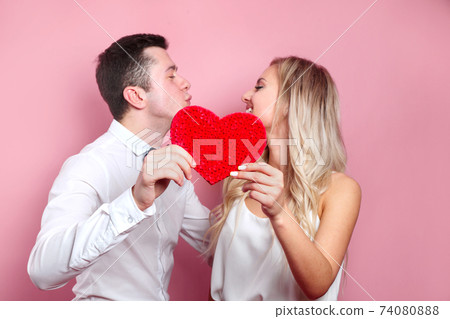 Valentines day. Young couple holding red love heart and kissing. Couple in love Valentines day. Young couple holding red love heart and kissing. Couple in love 74080888