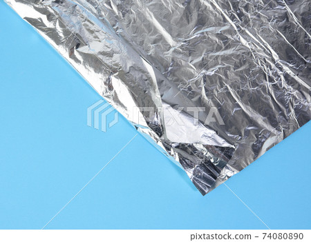 folded corner of gray food foil on brown background folded corner of gray food foil on brown background 74080890
