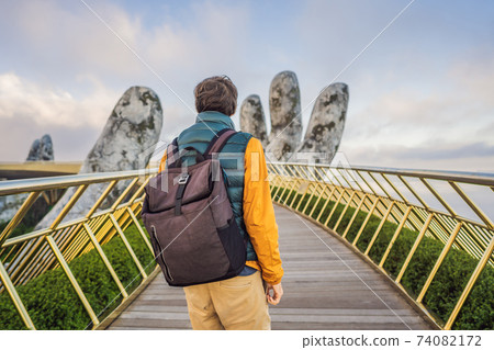 Young man tourist at Famous tourist attraction - Golden bridge at the top of the Ba Na Hills, Vietnam 74082172
