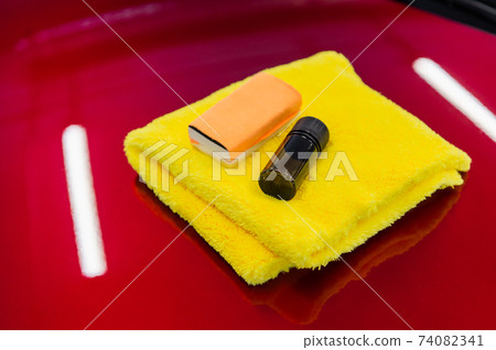 Close-up of a coating set: microfiber, sponge applicator and liquid glass nano protection to apply on a car hood. Preparing for applying special coating on a car surface. 74082341
