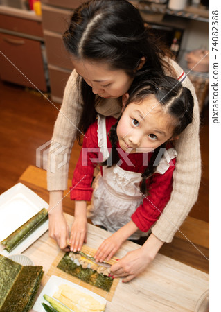 Mother and daughter making sushi rolls 74082388