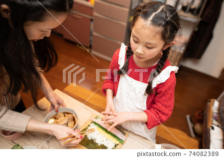 Mother and daughter making sushi rolls Mother and daughter making sushi rolls 74082389