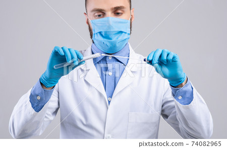 Medical doctor in face mask and gloves holding covid-19 PCR test tube on light grey studio background, panorama 74082965