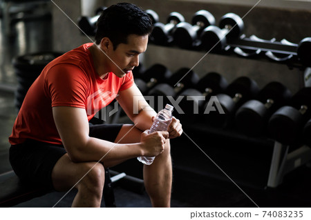 Muscle man break after dumbbell workout in gym 74083235