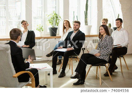 Male speaker giving presentation in hall at workshop. Audience or conference hall. Front view of attented listening participants. Male speaker giving presentation in hall at workshop. Audience or conference hall. Front view of attented listening participants. 74084556