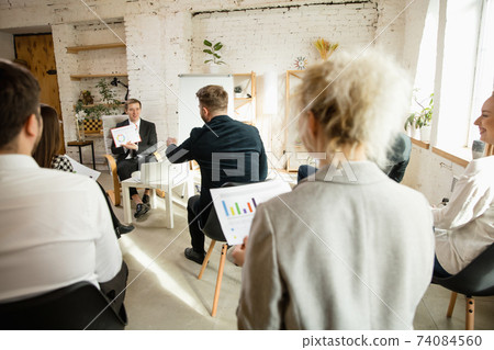 Male speaker giving presentation in hall at workshop. Audience or conference hall. Rear view of unrecognized participants. Male speaker giving presentation in hall at workshop. Audience or conference hall. Rear view of unrecognized participants. 74084560