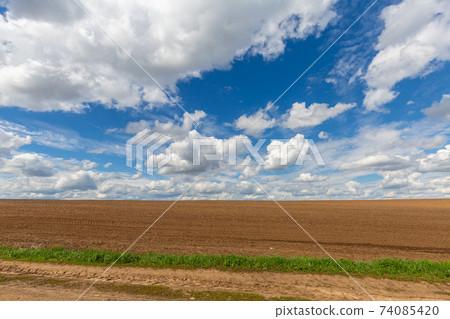 a plowed field against the sky with clouds. Spring sunny day a plowed field against the sky with clouds. Spring sunny day 74085420