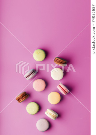 Colorful French macaroni cookies are scattered on a pink background. Colorful French macaroni cookies are scattered on a pink background. 74085687