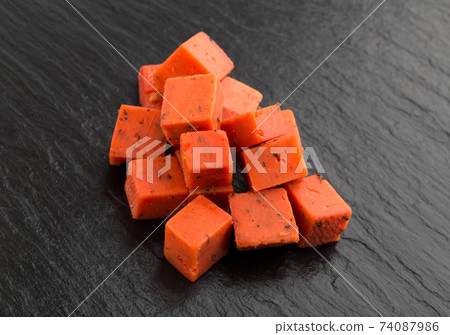 Cheese cubes of red color on a slate board. Cheese pesto closeup on the surface of the stone. 74087986