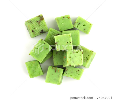 Cheese cubes of green color on a white background. Cheese pesto closeup on a white background.. Cheese cubes of green color on a white background. Cheese pesto closeup on a white background.. 74087991