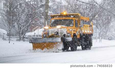Yellow snowplow clearing a road during a snow storm 74088810