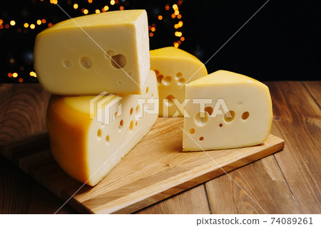 Cheese on table on the dark background. Medium hard cheese head edam, gouda, parmesan on wooden board. Healthy eating concept. 74089261