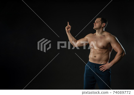 Man's hand points bare torso Young male male adult, attractive strong elegant model, successful elegance background black bodybuilder 74089772