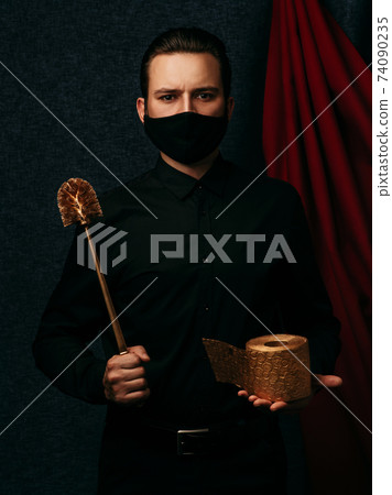 man with a gold toilet brush and a roll of toilet paper wearing a protective medical mask against coronovirus 74090235