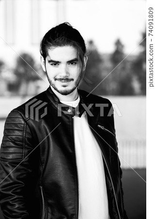Half length portrait of handsome bearded man dressed in fashionable clothes standing on street against while wall background with area for advertising content.Handsome hipster guy posing on copy space 74091809
