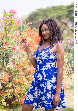 Content Black Woman Smelling Flowers in Park. Content Black Woman Smelling Flowers in Park. 74094077