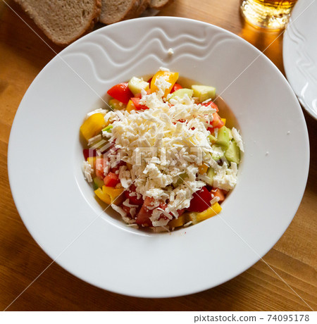 Dish of Balkan cuisine Shopska salad with cucumbers, tomatoes, bell peppers and brynza (salted sheep cheese) 74095178