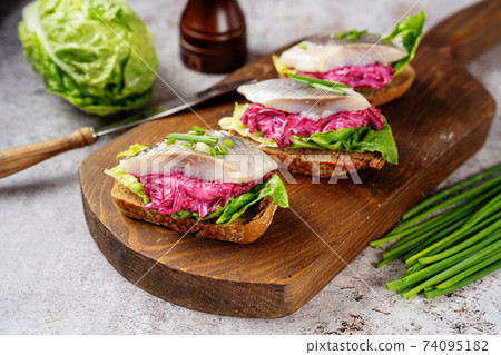 Three herring sandwiches on wooden board Three herring sandwiches on wooden board 74095182