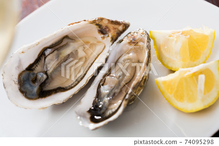 Tasty oysters with lemon on plate top view Tasty oysters with lemon on plate top view 74095298