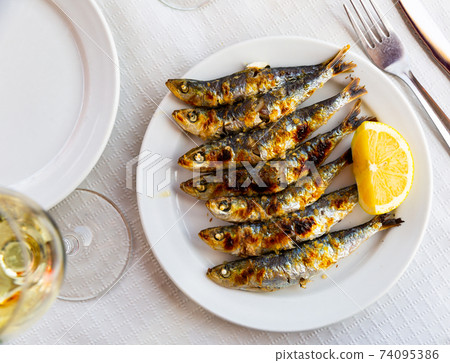 Espeto de sardinas with slice of lemon 74095386