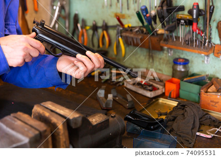 Disassembled smallbore sporting pistol in hands of gunsmith Disassembled smallbore sporting pistol in hands of gunsmith 74095531