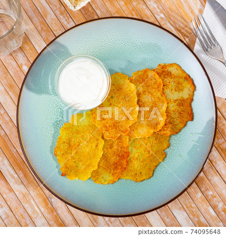 Draniki with sour cream at plate, dish of Belarusian cuisine Draniki with sour cream at plate, dish of Belarusian cuisine 74095648