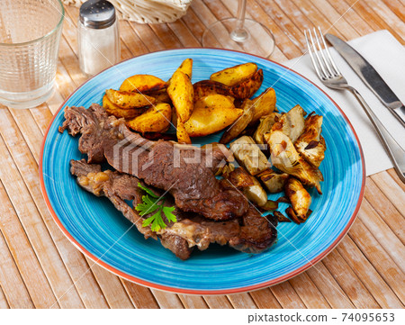 Veal steak with grilled potato and artichokes Veal steak with grilled potato and artichokes 74095653
