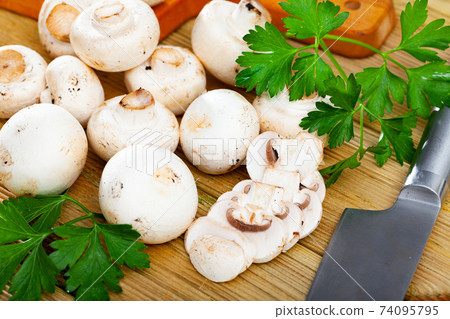 Closeup of whole raw fresh champignon mushroom on a white wooden table. Mushrooms as vegetable protein, raw food diet, vegetarianism 74095795