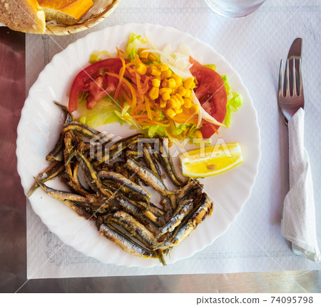 Dish of fried anchovy with tomatoes, corn and lemon, nobody Dish of fried anchovy with tomatoes, corn and lemon, nobody 74095798