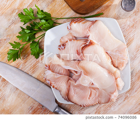 Pieces of fresh blue shark on wooden surface with greens Pieces of fresh blue shark on wooden surface with greens 74096086