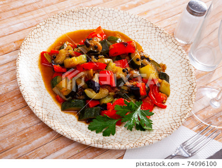 Plate of stewed vegetables on table. Vegetarian dish 74096100