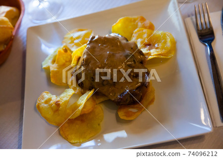 Pork cheeks served with potato chips 74096212