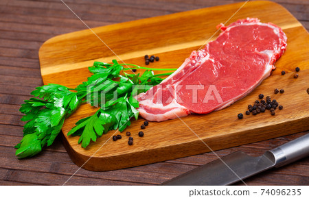 Piece of raw boneless beef with seasonings and greens Piece of raw boneless beef with seasonings and greens 74096235