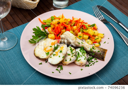Oven baked hake with vegetable garnish Oven baked hake with vegetable garnish 74096236