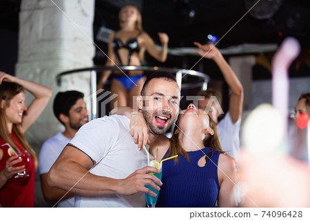 couple of smiling people together in the night club with drinks couple of smiling people together in the night club with drinks 74096428