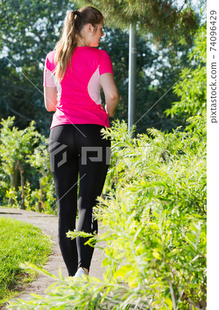 Female in pink T-shirt is jogging back 74096429