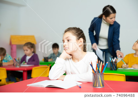 Sad schoolgirl in classroom during lesson 74096488
