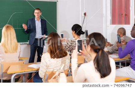 Professor explaining function graph to adult students in auditorium Professor explaining function graph to adult students in auditorium 74096747